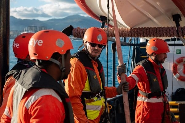 Das Rettungsteam in Ausrüstung mit Helm und Kleidung in Signalfarben auf dem Deck . Johannes Schweigler blickt in die Kamera.